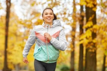 fitness, sport, people and healthy lifestyle concept - young woman running in autumn park. young woman running in autumn park