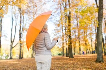 season, rainy weather and people concept - senior woman with umbrella at autumn park. senior woman with umbrella at autumn park
