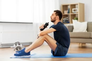 sport, fitness and healthy lifestyle concept - man drinking water from bottle during training at home. man drinking water during training at home