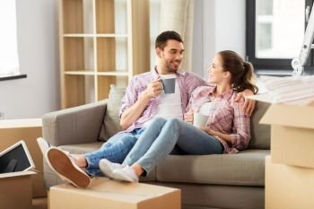 moving, people, repair and real estate concept - happy couple sitting on sofa and drinking coffee at new home. happy couple drinking coffee moving to new home
