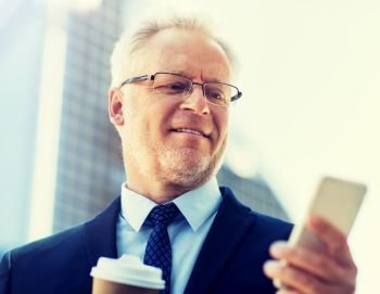 business, technology, communication and people concept - senior businessman with coffee cup and smartphone in city. businessman with smartphone and coffee in city