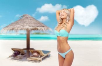 summer holidays, vacation and travel concept - young woman posing in bikini over tropical beach of maldives background. young woman posing in bikini on beach