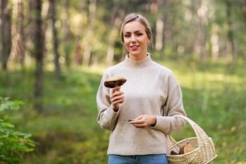 season and leisure people concept - young woman with basket and mushroom in autumn forest. young woman with mushroom in autumn forest