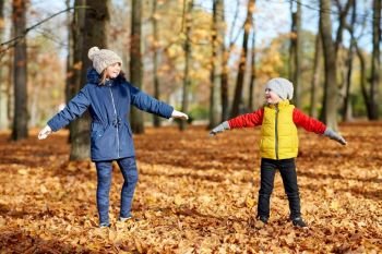childhood, season and people concept - happy children having fun at autumn park. happy children having fun at autumn park