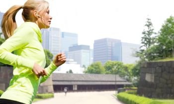 fitness, sport and healthy lifestyle concept - woman with earphones running and listening to music over city park background. woman with earphones running at city park