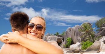 summer holidays, vacation and travel concept - happy couple hugging over tropical beach of seychelles island background. happy couple hugging on summer beach