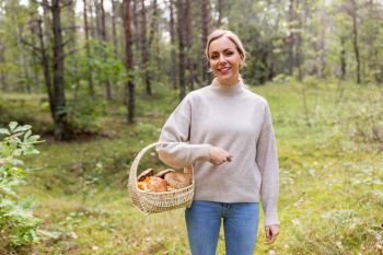 season and leisure people concept - young woman with mushrooms in wicker basket in forest. woman with basket picking mushrooms in forest