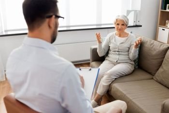 geriatric psychology, mental therapy and old age concept - senior woman patient talking to psychologist at psychotherapy session. senior woman patient talking to psychologist
