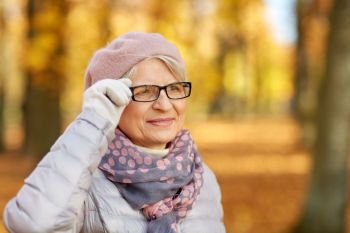 old age, retirement and season concept - portrait of happy senior woman in glasses at autumn park. portrait of happy senior woman at autumn park
