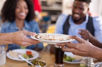 leisure, food and people concept - group of happy international friends eating at restaurant and male hands holding plate with chapati bread. international friends eating at restaurant