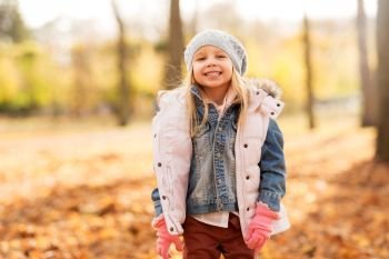 childhood, season and people concept - happy little girl at autumn park. happy girl at autumn park