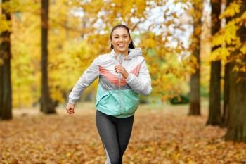 fitness, sport, people and healthy lifestyle concept - young woman running in autumn park. young woman running in autumn park