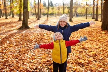 childhood, season and people concept - happy children on fallen leaves at autumn park. happy children at autumn park