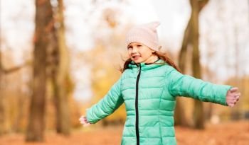 childhood, season and people concept - happy little girl at autumn park. happy girl at autumn park