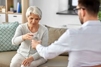 geriatric psychology, mental therapy and old age concept - psychologist giving glass of water to sad unhappy senior woman client at psychotherapy session. psychologist giving glass of water to senior woman