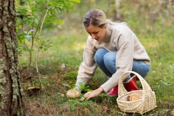 season and leisure people concept - young woman with basket picking mushrooms in autumn forest. young woman picking mushrooms in autumn forest