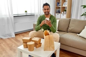 communication, leisure and people concept - indian man using smartphone for takeaway food order check up at home. indian man checking takeaway food order at home