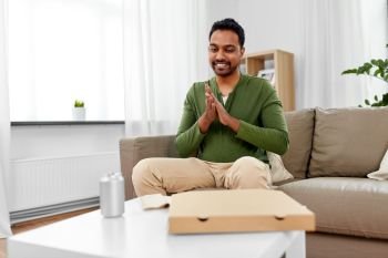 food delivery, consumption and people concept - excited indian man looking inside of takeaway pizza box at home. indian man looking inside of takeaway pizza box