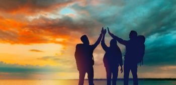 travel, tourism and hike concept - group of travellers with backpacks making high five over sunset background. travellers making high five over sunset