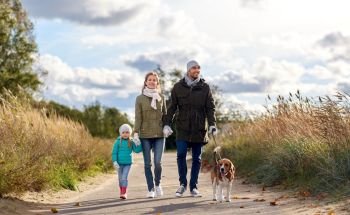family, pets and people concept - happy mother, father and little daughter walking with beagle dog on leash in autumn. happy family walking with beagle dog in autumn