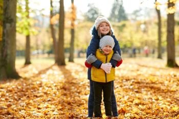 childhood, season and family concept - happy children hugging at autumn park. happy children hugging at autumn park