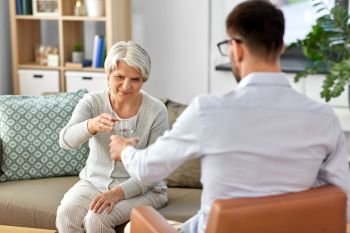 geriatric psychology, mental therapy and old age concept - psychologist giving glass of water to sad unhappy senior woman client at psychotherapy session. psychologist giving glass of water to senior woman