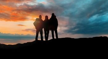 travel, tourism and hike concept - group of travellers with backpacks over sunset background. group of travellers with backpacks over sunset