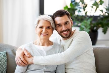 family, generation and people concept - happy smiling senior mother with adult son hugging at home. senior mother with adult son hugging at home