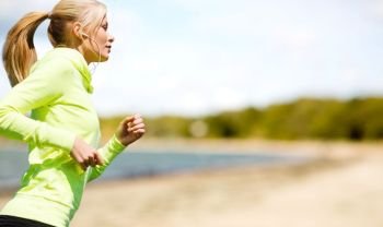 fitness, sport and healthy lifestyle concept - woman with earphones running and listening to music over summer beach background. woman with earphones running at park