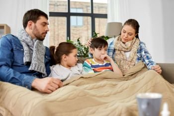 family, health problem and people concept - ill father, mother, daughter and son having flu sharing paper tissues at home. ill family with children having flu at home