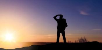 travel, tourism and hike concept - silhouette of male tourist looking far away over sunset background. silhouette of tourist looking far away over sunset