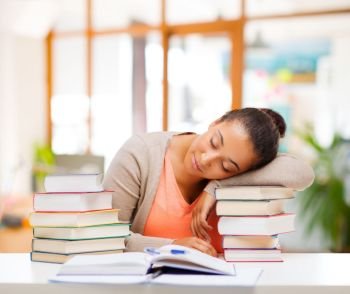education, learning and people concept - tired african american female student sleeping on books over school background. tired african female student sleeping on books