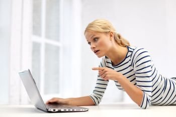 communication, technology and people concept - young woman having video call and pointing finger to laptop computer at home. woman having video call on laptop computer at home