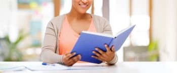 education, learning and people concept - african american female student reading book over school background. african american female student reading book