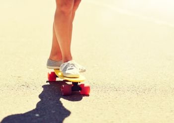 summer, extreme sport and people concept - legs of teenage girl or young woman riding skateboard on road. legs of young woman riding skateboard on road