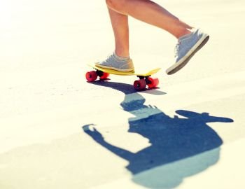 summer, extreme sport and people concept - male legs riding short modern cruiser skateboard along crosswalk. male legs riding short skateboard along crosswalk