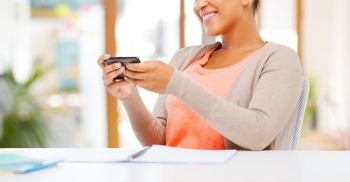 education, business and technology concept - smiling african american woman with smartphone over office background. african american woman with smartphone