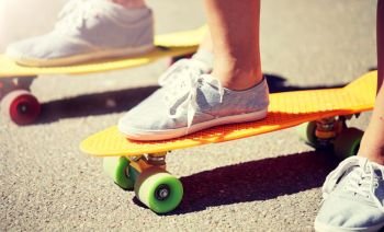skateboarding, leisure, extreme sport and people concept - close up of young woman legs riding short modern cruiser skateboard on road. close up of female feet riding short skateboard