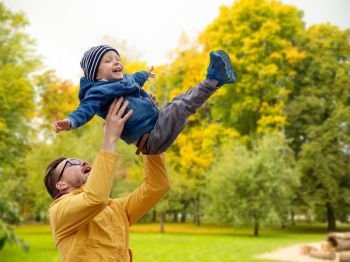 family, childhood and fatherhood concept - happy father and little son playing and having fun outdoors over autumn park background. father with son playing and having fun in autumn
