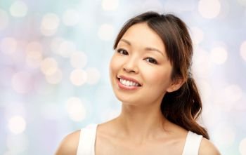beauty and people concept - face of happy smiling young asian woman over festive lights background. face of happy smiling young asian woman