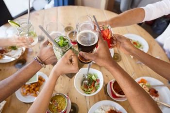 leisure, food and people concept - group of happy international friends eating and clinking glasses at restaurant table. friends eating and clinking glasses at restaurant