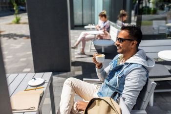 travel, tourism and lifestyle concept - indian man drinking coffee at city street cafe. indian man drinking coffee at city street cafe