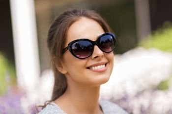 summertime, leisure and people concept - portrait of happy young woman in sunglasses at summer garden. happy young woman in sunglasses at summer garden