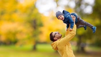 family, childhood and fatherhood concept - happy father and little son playing and having fun outdoors over autumn park background. father with son playing and having fun in autumn