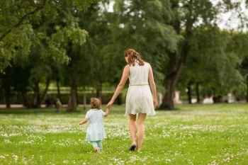 family, childhood and parenthood concept - mother with little baby daughter walking at summer park. mother with baby daughter walking at summer park