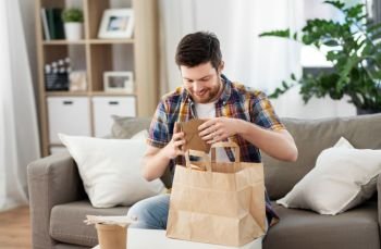 consumption, eating and people concept - smiling man unpacking takeaway food at home. smiling man unpacking takeaway food at home
