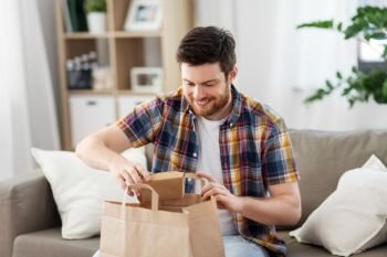 consumption, eating and people concept - smiling man unpacking takeaway food at home. smiling man unpacking takeaway food at home