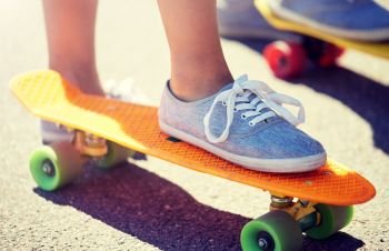 skateboarding, leisure, extreme sport and people concept - close up of young woman legs riding short modern cruiser skateboard on road. close up of female feet riding short skateboard