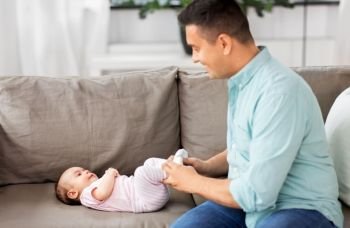 family, parenthood and fatherhood concept - happy smiling middle aged father playing with little baby daughter lying on sofa at home. middle aged father playing with baby at home