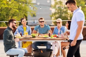 leisure and people concept - happy friends having bbq party on rooftop in summer. happy friends having bbq party on rooftop